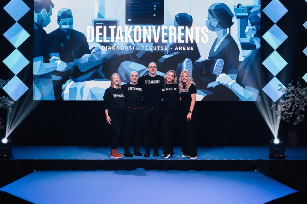 Viieliikmeline Deltakutse tiim mustades pluusides Deltakonverentsi laval